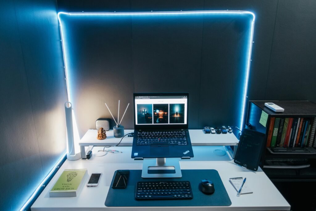 A modern home office desk setup with a laptop, books, and LED lighting for productivity.